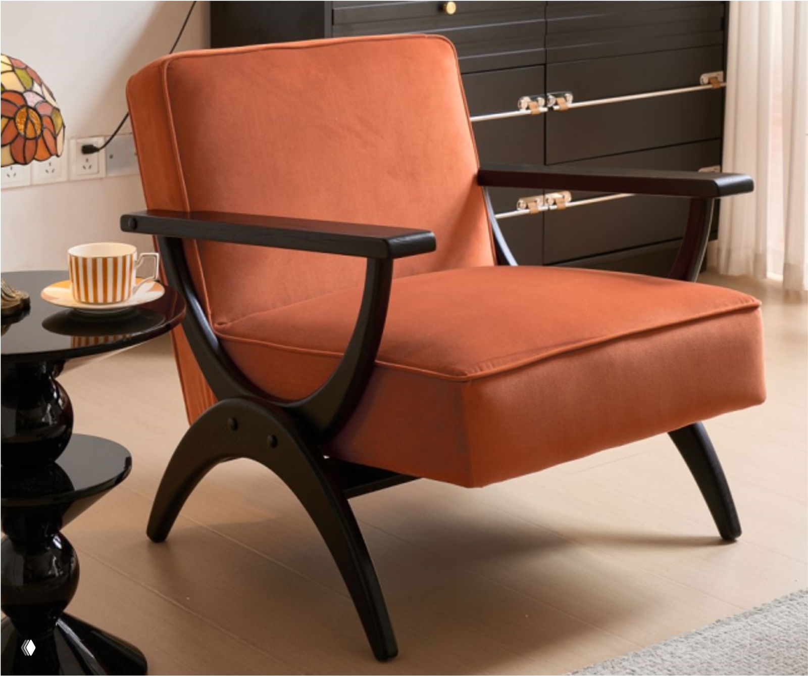 Кресло из массива дуба с терракотовой обивкой в жилом интерьере, видна деревянная конструкция подлокотников, рядом журнальный столик и чашка.