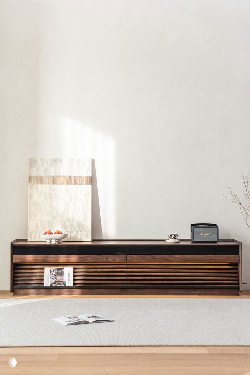 Тёмно-коричневая тумба под ТВ из массива дуба в светлом минималистском интерьере: декор, радиоприёмник и мягкий ковер на полу.