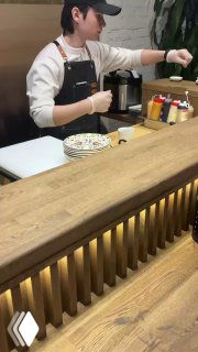 Кадр видеоподачи: шеф за барной стойкой в фартуке готовит и подает блюда гостям прямо на глазах, атмосферный момент сета.