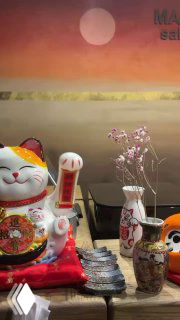 Декор на стойке: манэки-нэко, вазы и фигурки на фоне фирменного панно Masse Omakase — финальный вид пространства ресторана.