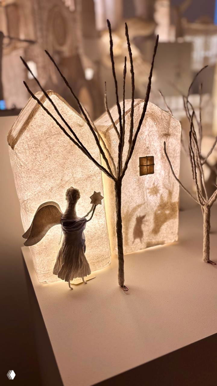Миниатюрные домики и светящиеся фигурки ангелов и котов из папье‑маше, детальная рождественская сцена экспозиции Дины Хайченко в музее.