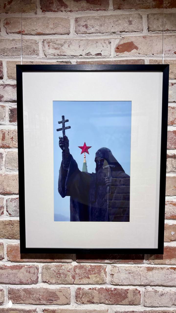 Фотография в раме: статуя с крестом на фоне кремлёвской звезды — работа документальной выставки Тофика Шахвердиева, снято в музее.