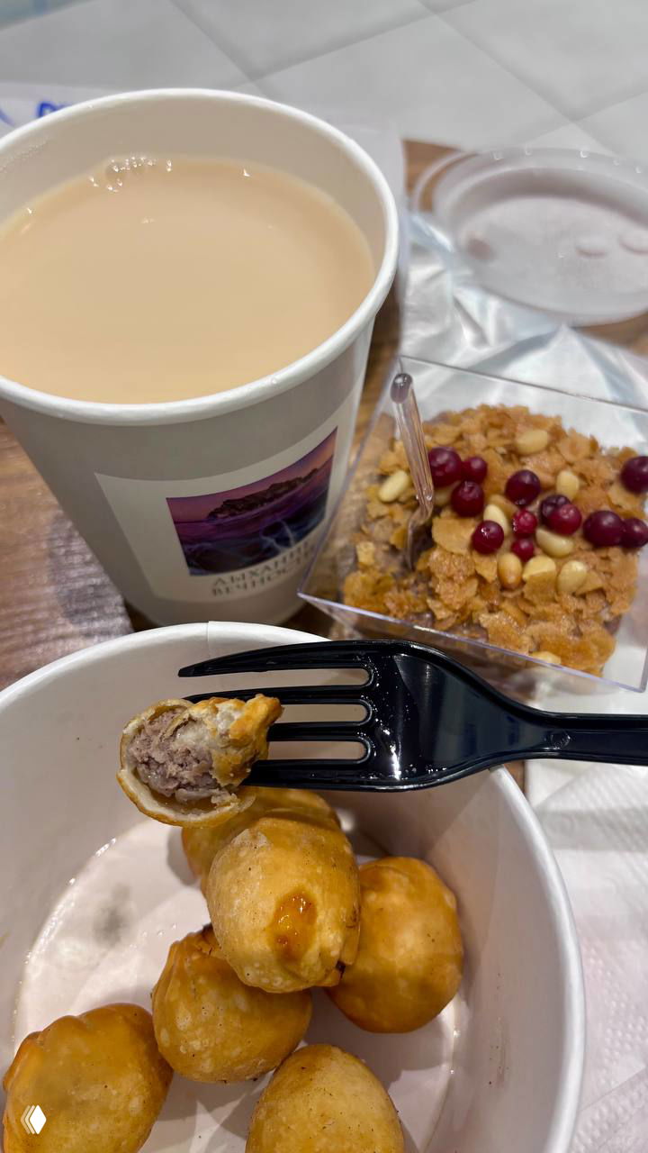 Чашка с бурятским чаем с молоком на фоне десерта и чаши с банши; вилка раскрывает одну банши, видна начинка