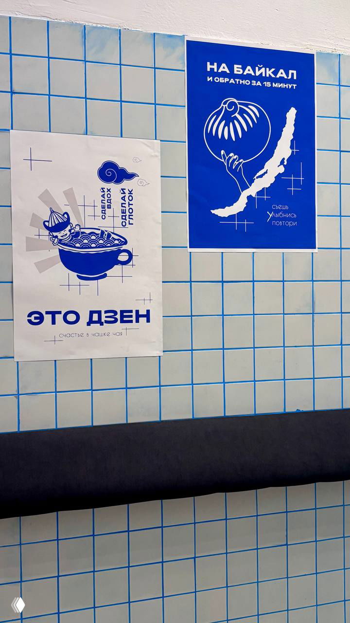 Стена с синими плакатами и плиточной отделкой; постеры про Байкал и буузы создают тематический интерьер заведения