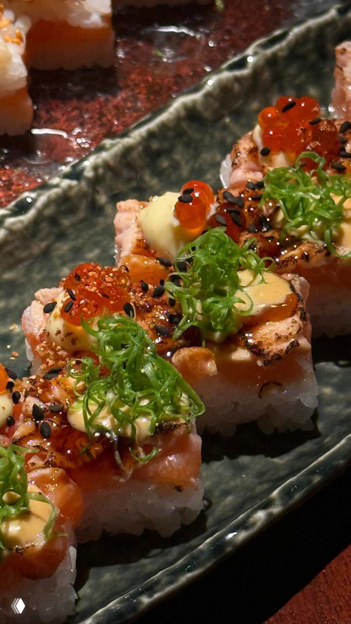 Крупный план обжаренных роллов с икрой и зеленью: кремовый соус, икорные шарики и тонко нарезанный зелёный лук сверху, аппетитная текстура.