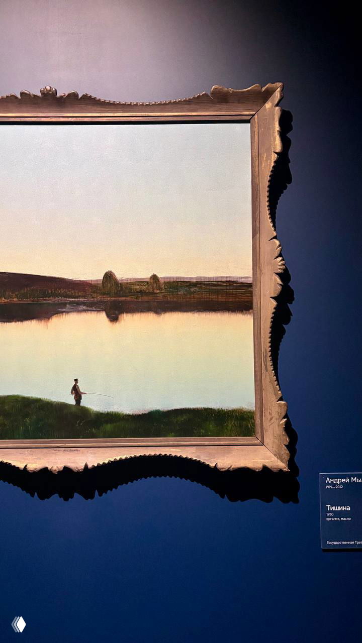 Крупный план картины в раме с отражённым в воде ровным пейзажем; часть золотистой резной рамы и подпись работы на стене экспозиции.