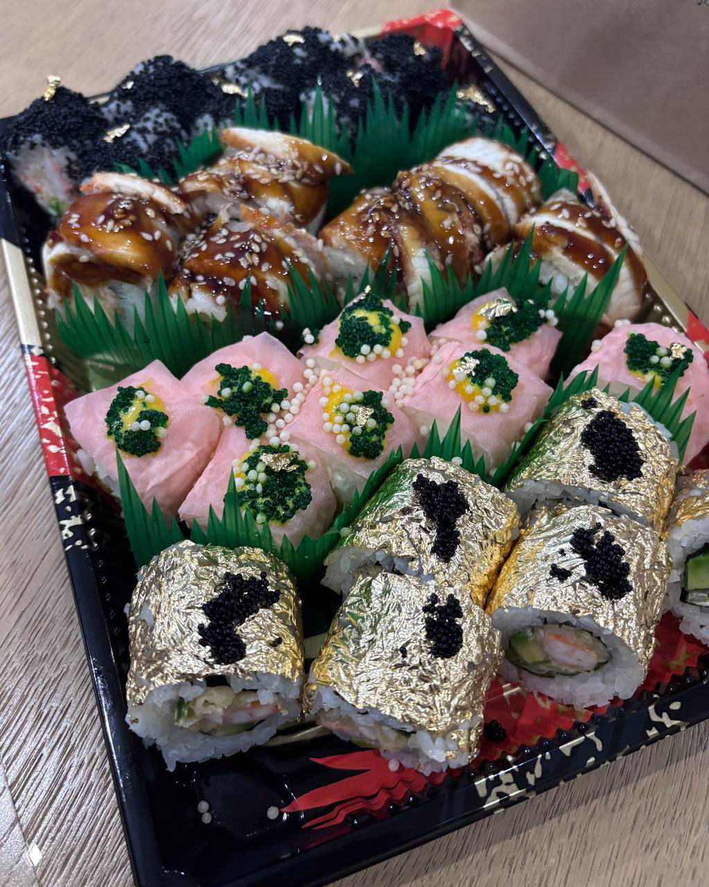 Большой набор роллов в подарочной коробке: золотая фольга, икринки и декор — демонстрация «премиального» оформления одного из заказов