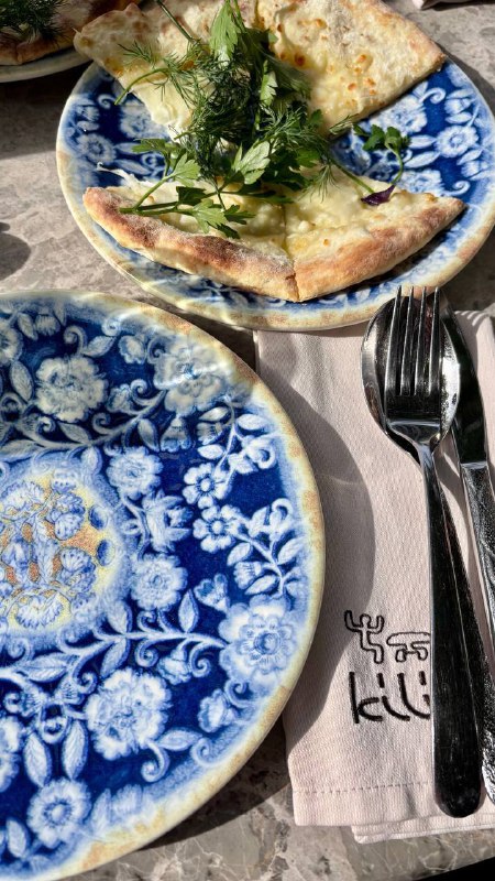 Купольная мозаичная печь в кухне ресторана, рабочая поверхность рядом, кухонные принадлежности и металлические приборы в кадре.