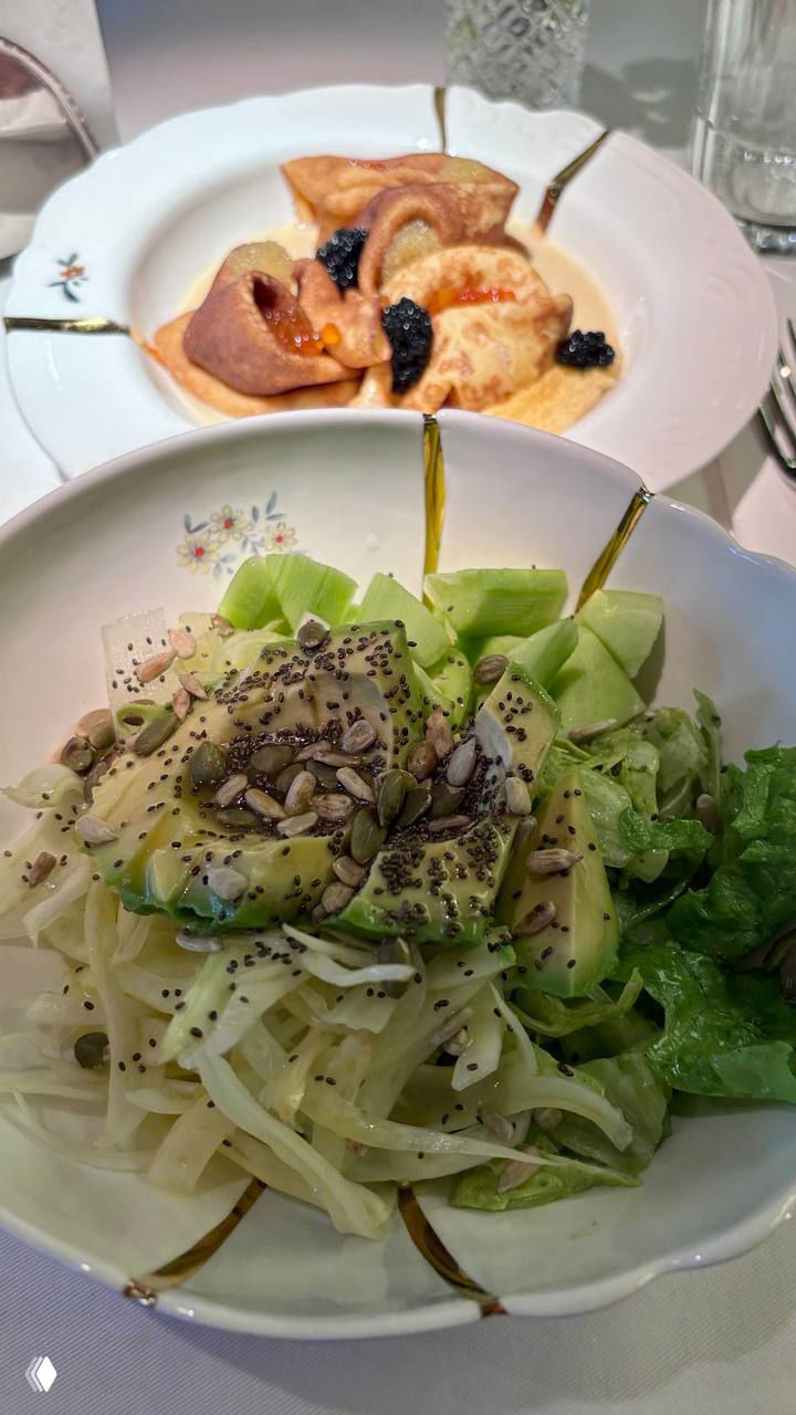 Крупный план порции блинчиков с икрой и соусом, разные формы и текстуры на тарелке, акцент на икре и ресторанной эстетике подачи.