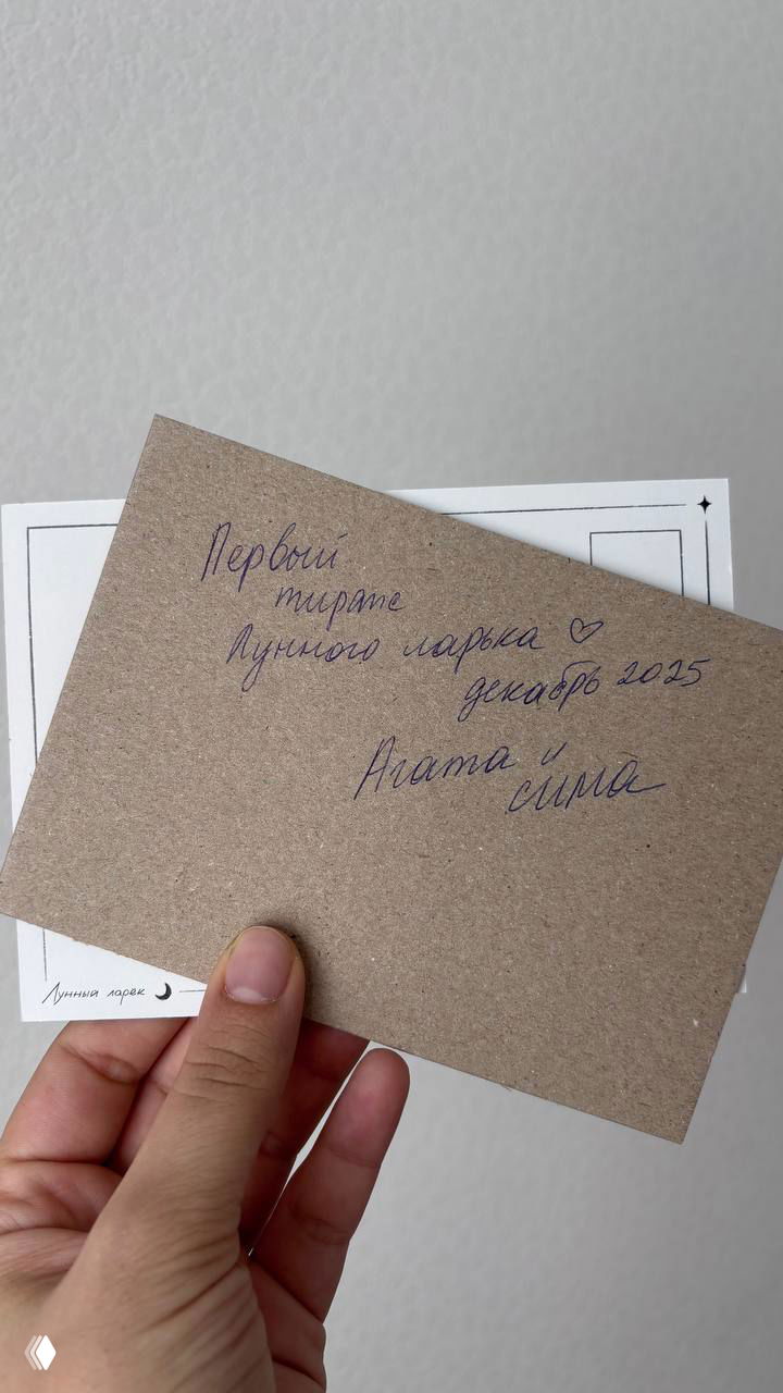 Открытка со снежной зимней сценой и девушкой в тёплом платье, уложенная на подарок в крафтовой упаковке с красной шнуровкой — праздничная композиция.