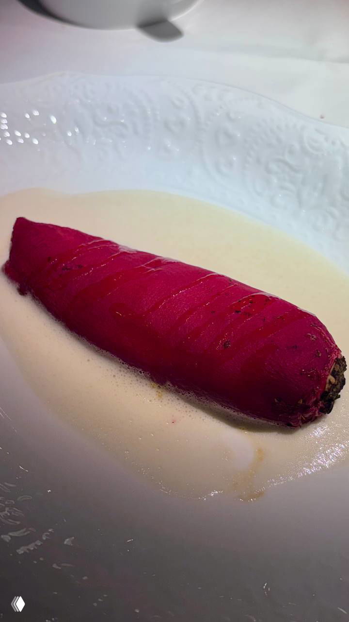 Интерьер ресторана с цветочными обоями и зеркалами, видна столовая зона с розовыми букетиками и бархатными креслами — театральная атмосфера бистро.