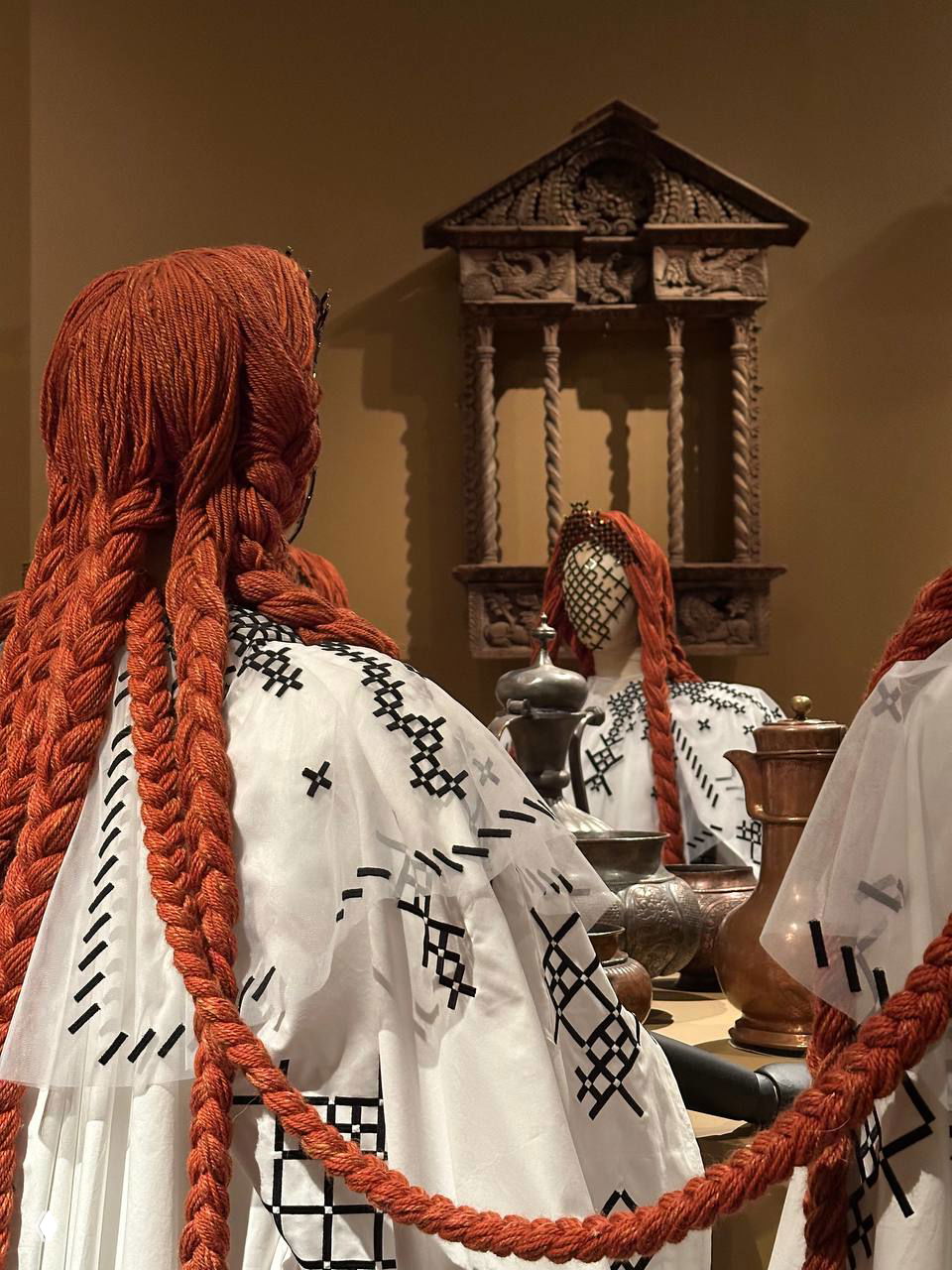 Манекены в белых одеждах с длинными рыжими косами, отражения в зеркале и антикварная резная полка — деталь костюмов Алёны Ахмадуллиной.