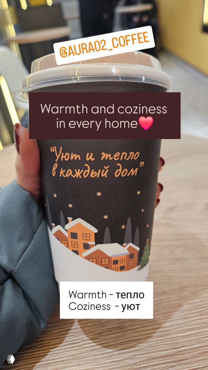 Крупный план на стакан с надписью «Уют и тепло в каждый дом», сердечко-стикер и подписи на английском и русском рядом с чашкой.