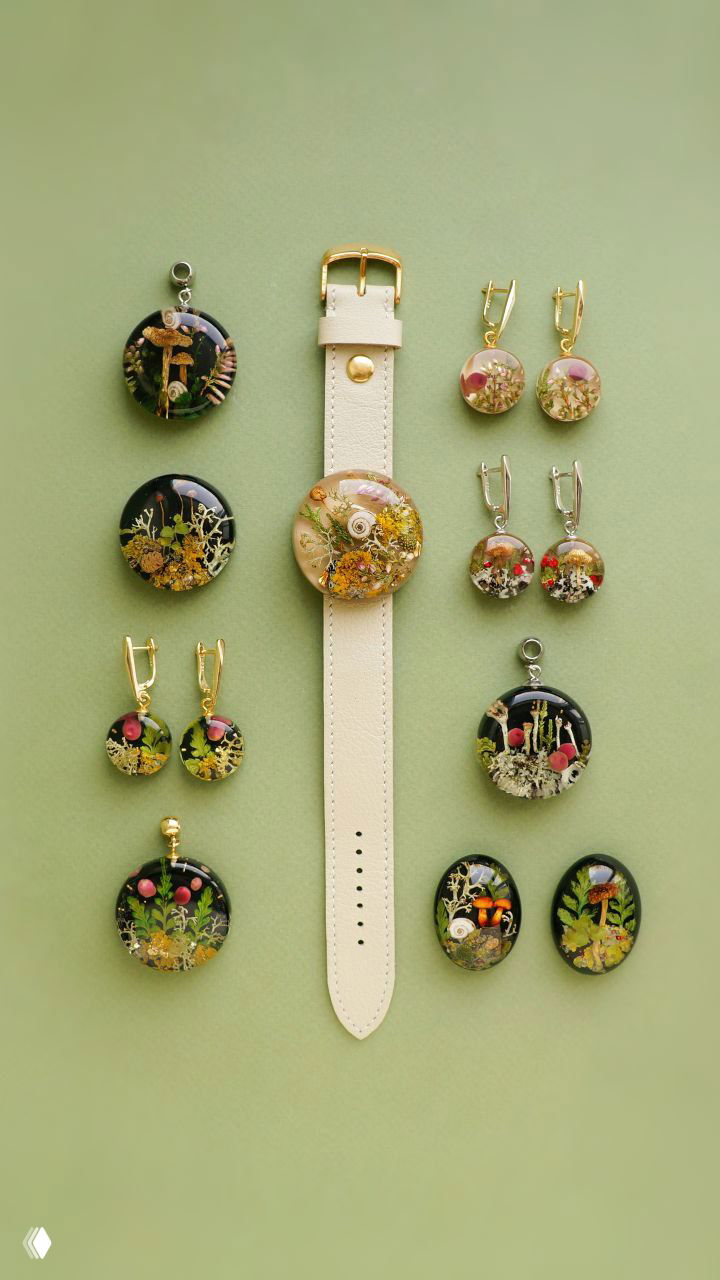 Расположенные в сетке маленькие смоляные кабошоны и пара круглых вставок вокруг ремешка часов — натюрморт с засушенными травами и цветами на зелёном фоне.