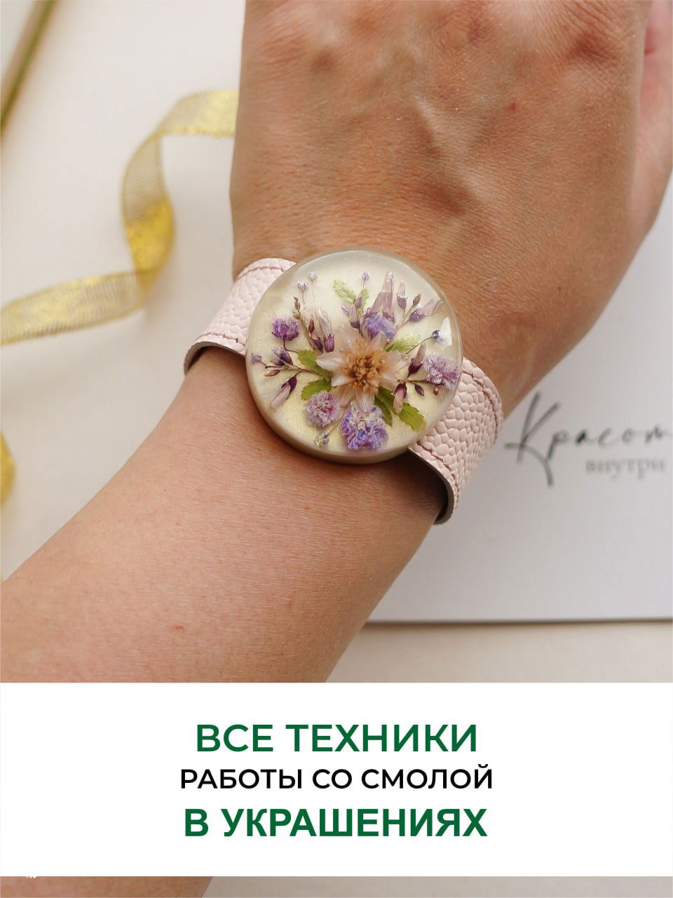 Рука с браслетом, в котором внутри прозрачной смолы расположены нежные сиреневые и бежевые цветы, изображение подчёркивает аккуратность инкрустации и форму изделия.