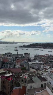 Панорамный вид на Стамбул с высоты: крыши домов, пролив с кораблями и облачное небо, снятое с уровня Галатской башни.