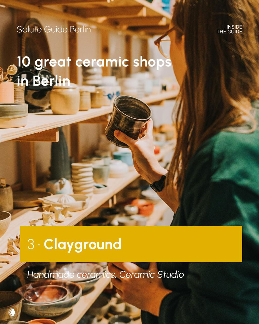Person holding and examining a handmade ceramic cup in a Berlin studio shop, browsing shelves of pottery under warm light, candid retail moment.