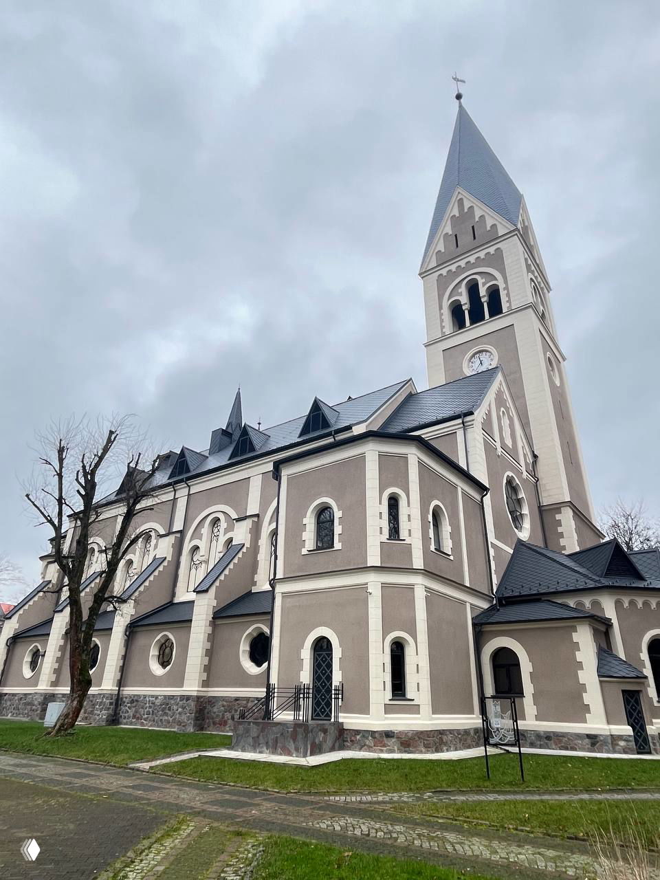 Кадр кирхи памяти Королевы Луизы со стороны: боковой неороманский фасад с круглыми окнами и восстановленной кровлей под серым небом.