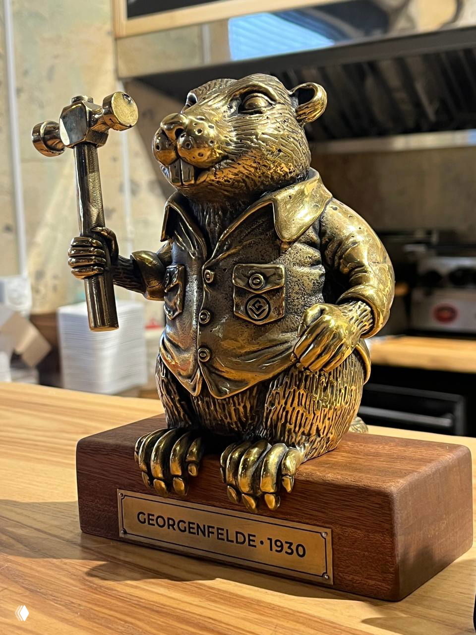 Крупный план бронзового бобра с молотком на деревянном постаменте с табличкой GEORGENFELDE 1930 — декоративный трофей в интерьере.