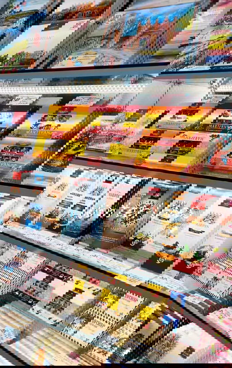Полка сувенирного магазина с коробками калининградского марципана разных брендов (Pomatti, M.Zappa) и подарочной упаковкой, вид товара на витрине.