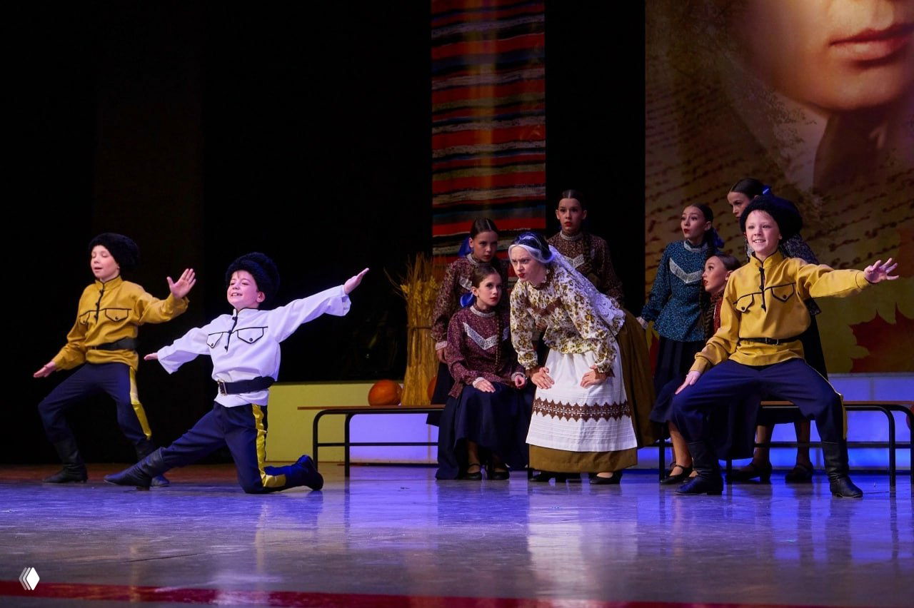 Сцена с танцевальной постановкой: дети в народных и условно военных костюмах исполняют номер театра танца «Жемчужинки» во время представления.