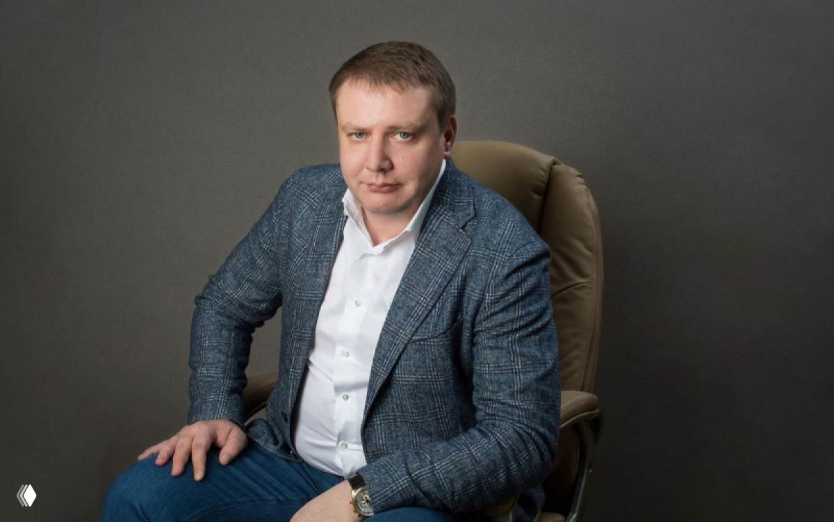 Студийный портрет сидящего мужчины в пиджаке и рубашке на нейтральном фоне — деловой образ для профиля бизнеса.