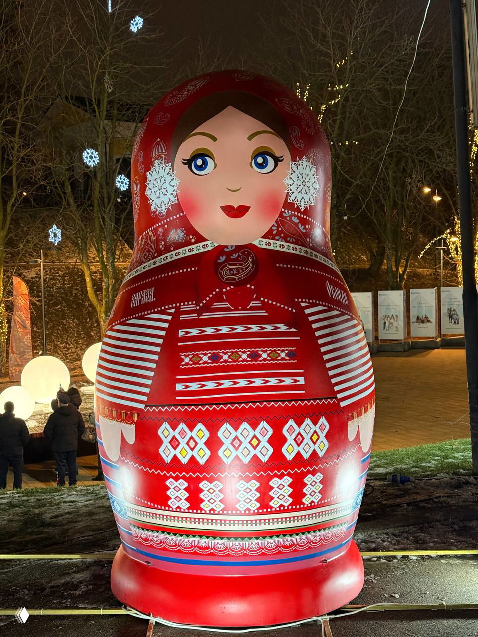Крупный план красной матрёшки с характерными орнаментами и снежинками, установленной на праздничной площадке в Рязани.