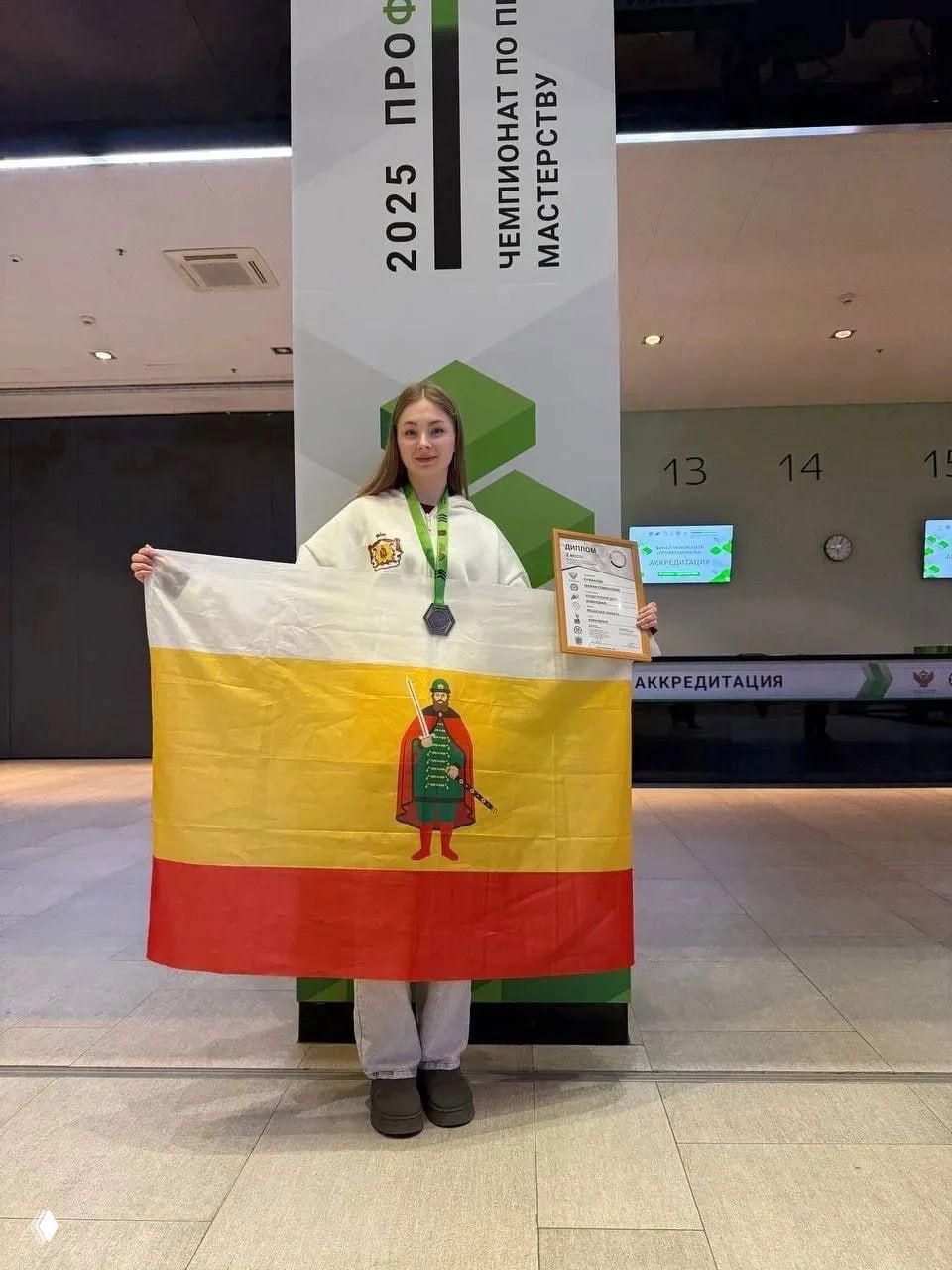 Мария Ермакова с медалью и флагом Рязанской области на фоне баннера чемпионата «Профессионалы» в Санкт-Петербурге
