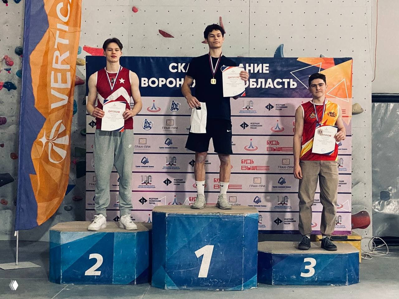 Пьедестал с тремя юниорами: победитель в центре и бронзовые призёры по бокам на Первенстве ЦФО по скалолазанию в Воронеже.