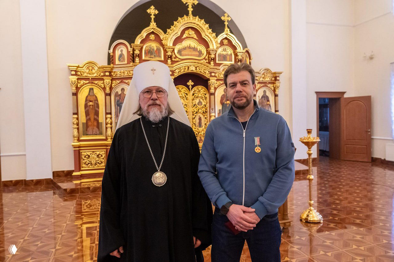 Митрополит Марк рядом с предпринимателем Андреем Игоревичем Матвеевым, награждённым медалью III степени; интерьер с золотым иконостасом и полированным полом.