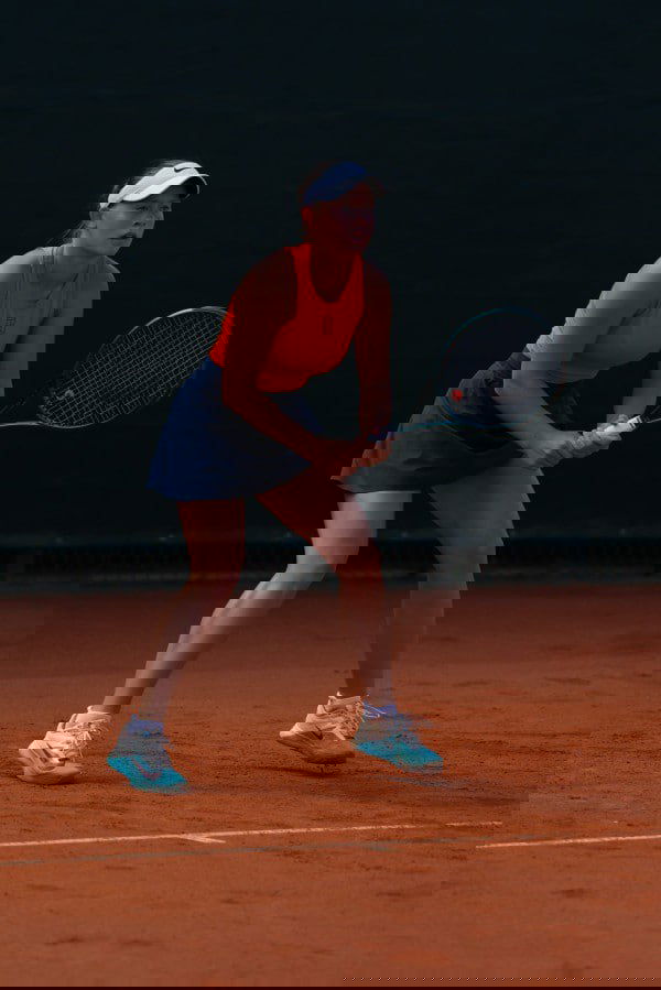 15‑летняя рязанская теннисистка Алиса Терентьева в оранжевом топе и тёмной юбке на корте, готовится к приёму мяча во время турнира.