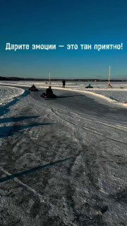 Заснеженная ледовая трасса с людьми на технике и надписью «Дарите эмоции — это так приятно!», рекламное фото проката.