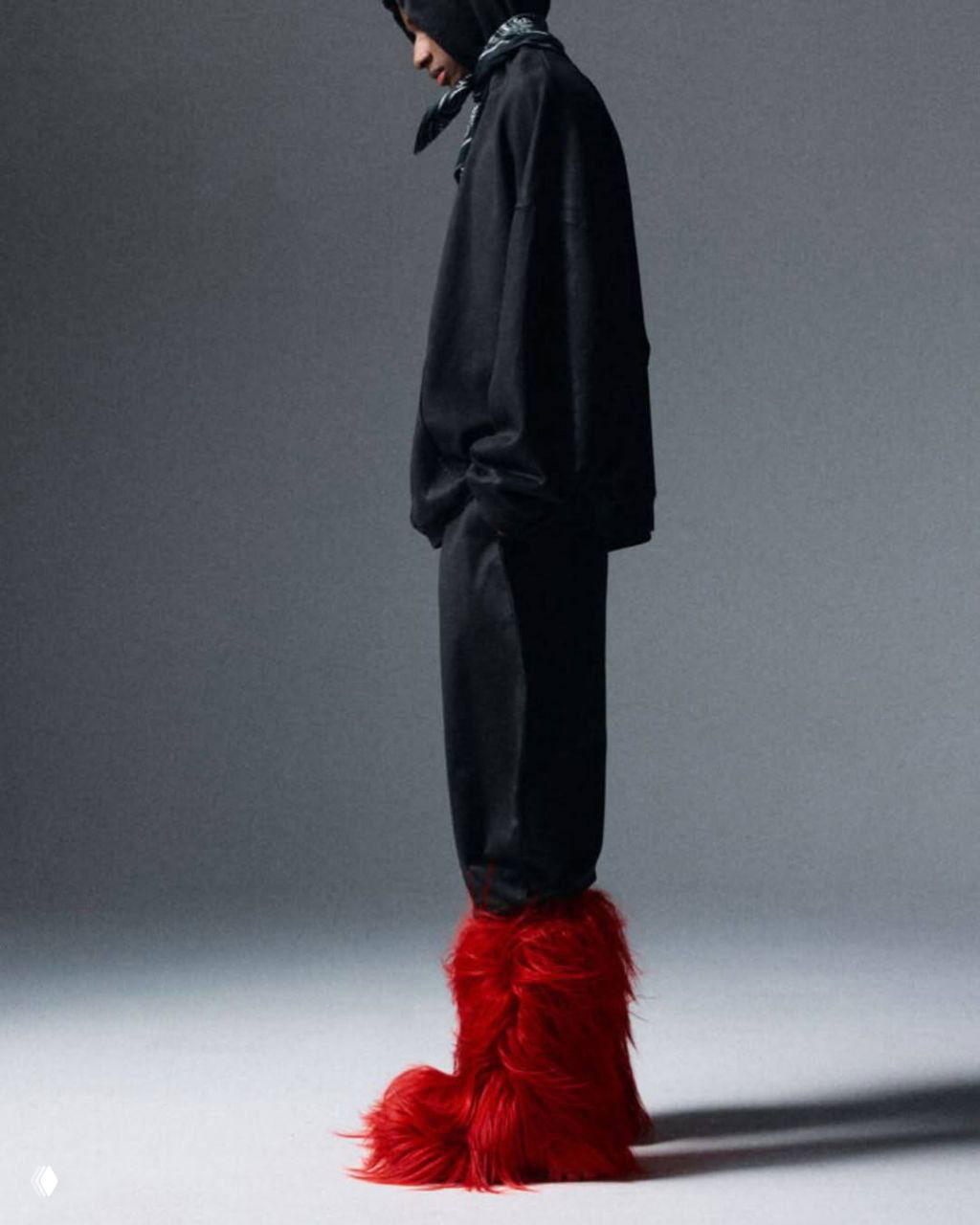 Модель в чёрном свободном спортивном костюме демонстрирует высокие красные пушистые ботинки Christian Louboutin в студийной постановке — общий вид образа.