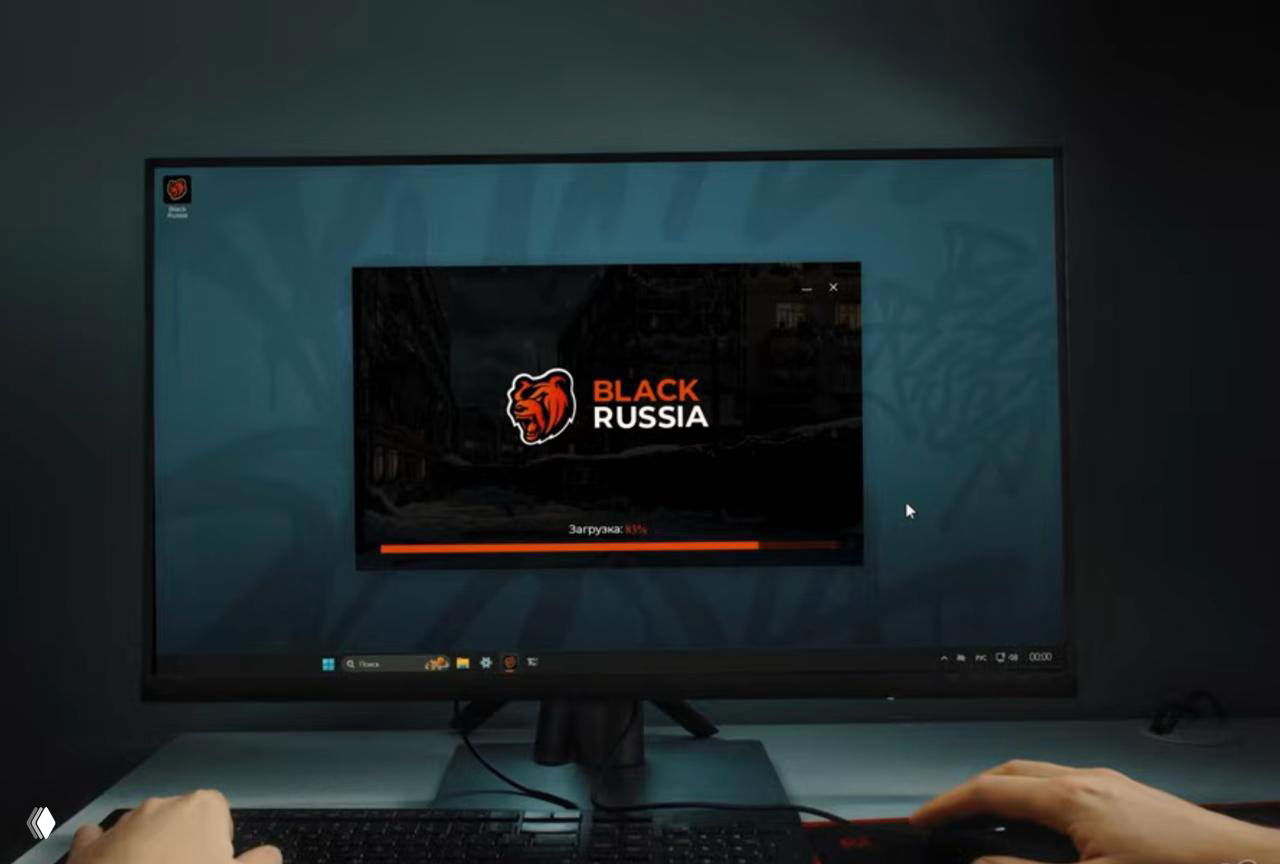 Монитор с экраном загрузки Black Russia и руки игрока за клавиатурой на столе — визуализация возможной ПК‑версии игры и интерфейса загрузки.