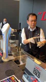 Сотрудник демонстрирует подачу напитка на стенде Asahi: сотрудник в униформе наливает пиво рядом с дегустационной станцией.