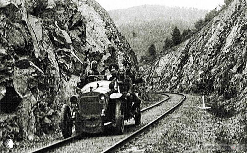 Автомобиль едет по рельсовому полотну Китайско-Восточной железной дороги между скальными стенами; видно, что колёса идут по рельсам.