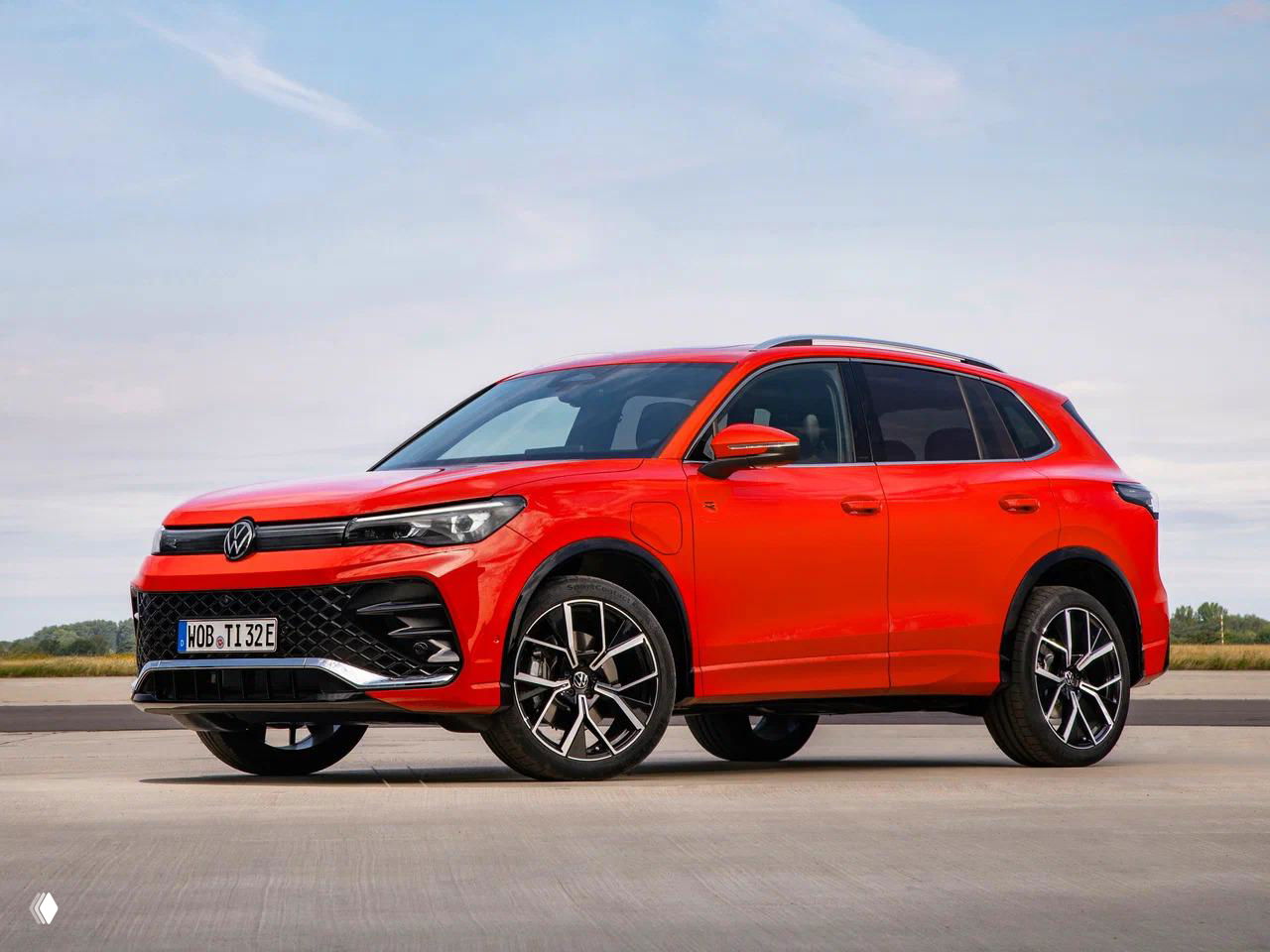 Красный Volkswagen Tiguan в динамике на открытой площадке, профиль кроссовера подчёркивает клиренс и спортивные колёса на лёгкосплавных дисках