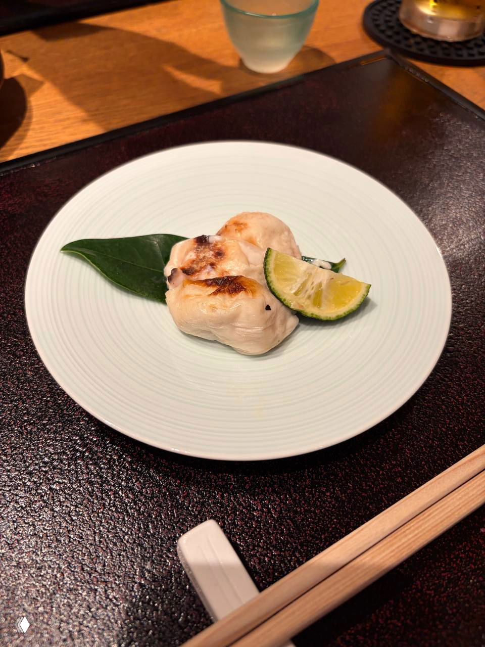 Небольшая жареная порция на листе с долькой лайма, светлая текстура и поджаренные участки — аккуратная порционная подача блюда.
